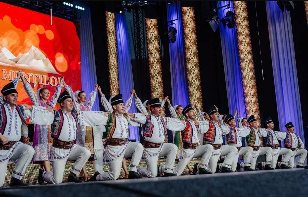 Ansamblul Folcloric Tarabostes interpretând dansuri populare românești pe o scenă mare, în costume tradiționale autentice