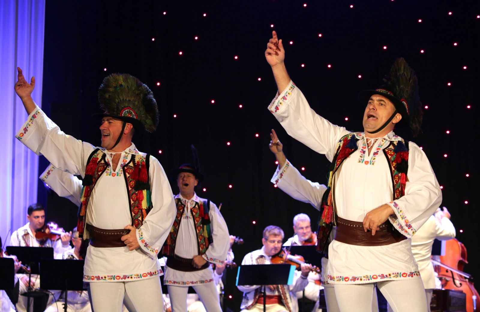 Dansatori ai Ansamblului Folcloric Tarabostes interpretând joc popular românesc pe scenă, în costume tradiționale autentice